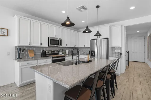 a kitchen with stainless steel appliances granite countertop a stove a refrigerator a microwave a island a dining table and chairs