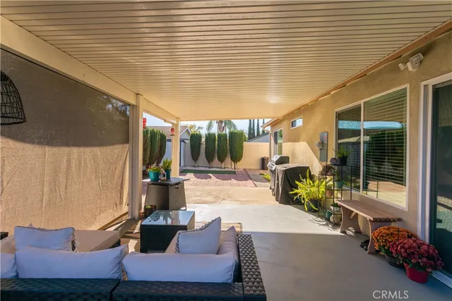 a view of a patio with table and chairs potted plants and floor to ceiling window