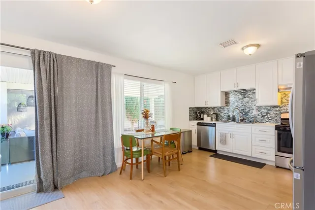 a kitchen with a dining table chairs and refrigerator