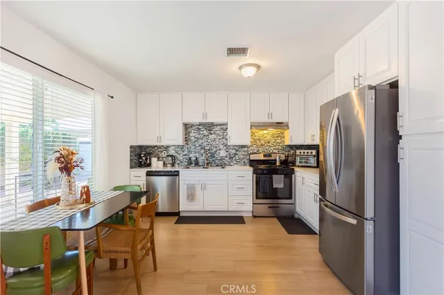 a kitchen with a refrigerator cabinets dining table and chairs