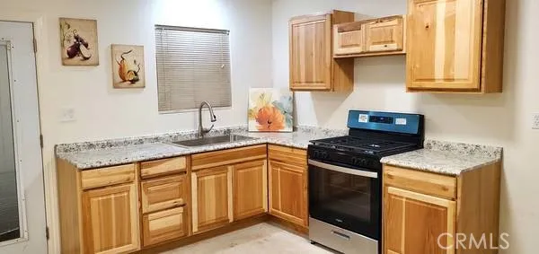 a kitchen with granite countertop a sink a stove and cabinets