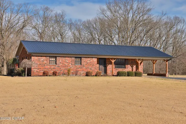 a backyard of a house with large trees and plants