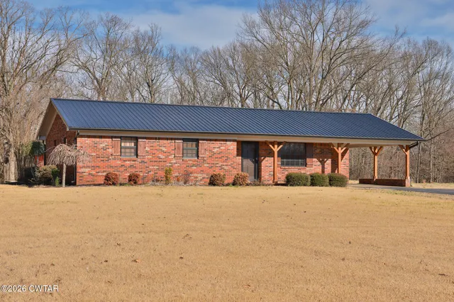 a backyard of a house with large trees and plants