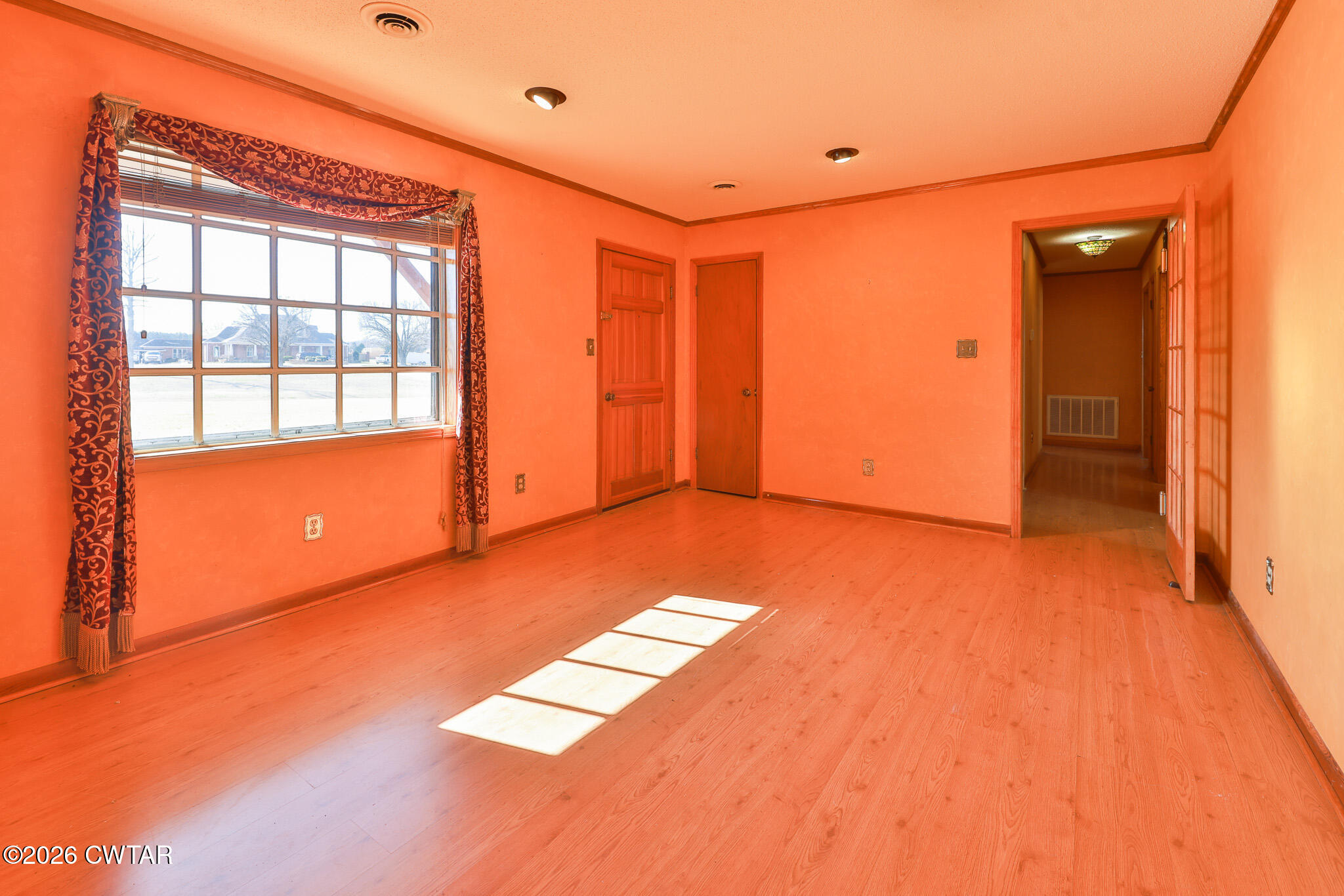 295 Adams Road Greenfield, TN 38230 - Photo 8 of 35 an empty room with wooden floor and windows with curtains