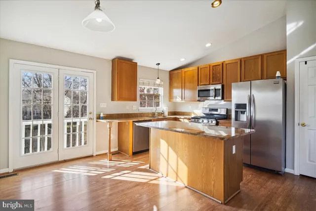 a kitchen with stainless steel appliances granite countertop a refrigerator a oven a sink with wooden floors and cabinets