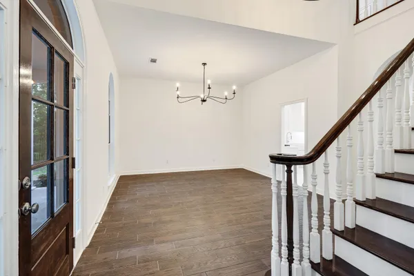 an empty room with chandelier fan and windows