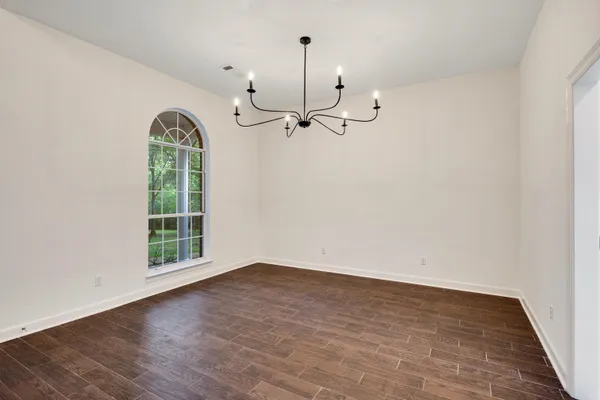 an empty room with wooden floor fireplace and windows