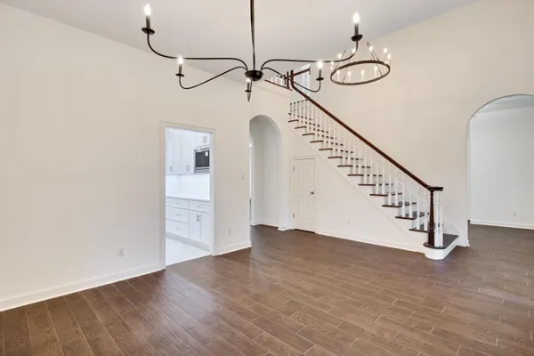 a view of an empty room with wooden floor and kitchen