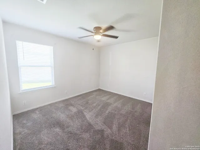 an empty room with closet and a ceiling fan