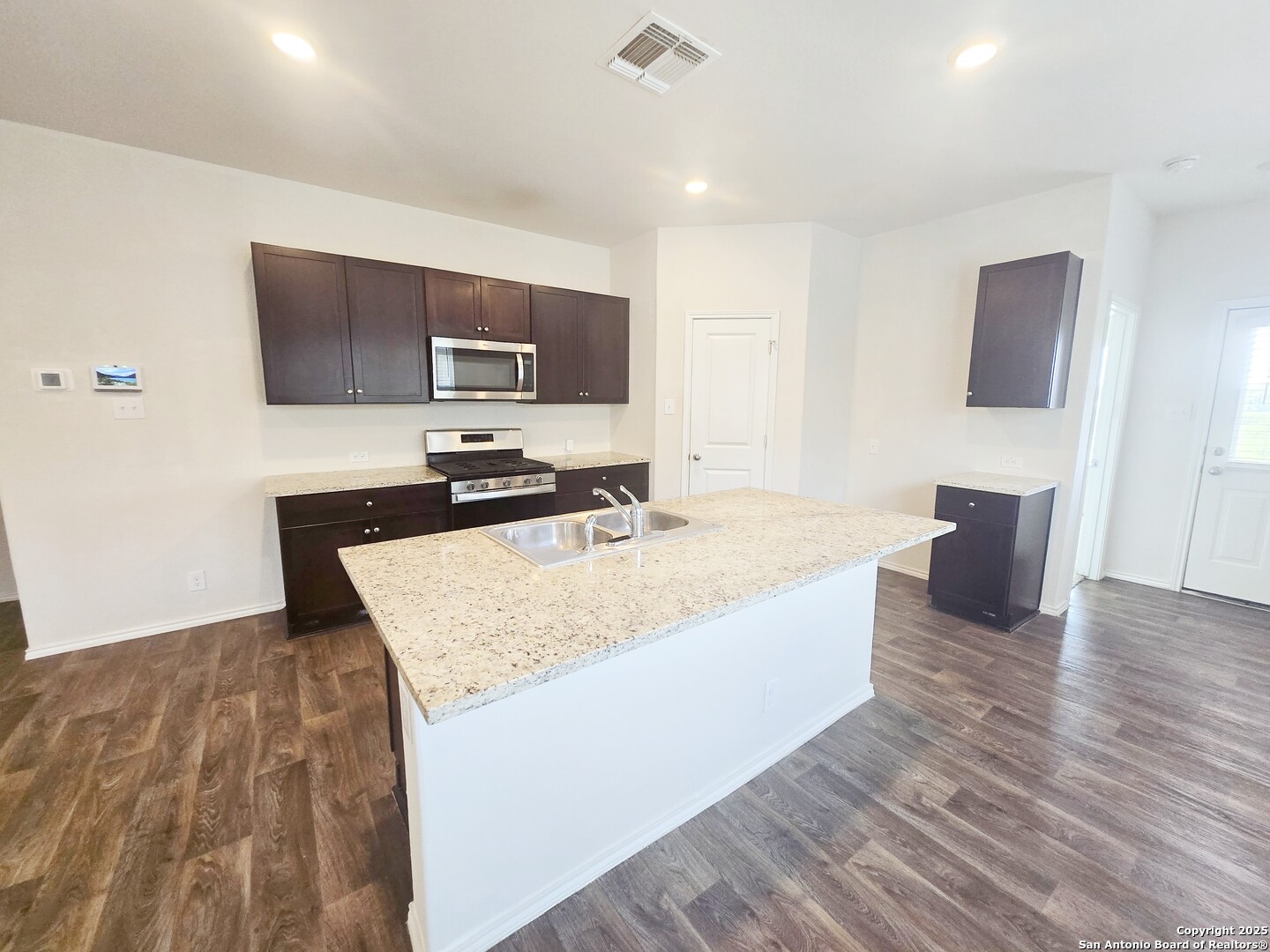 437 Middle Grn Loop Floresville, TX 78114 - Photo 6 of 25 a kitchen with kitchen island stainless steel appliances a sink and a refrigerator