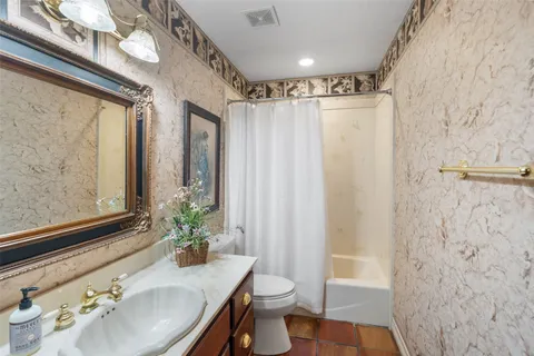 a bathroom with a granite countertop sink a toilet and shower curtain