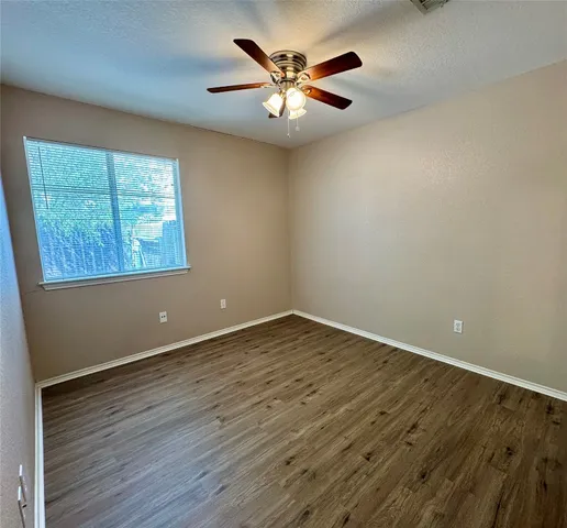 a view of an empty room with window and wooden floor