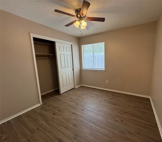 a view of an empty room with window and wooden floor