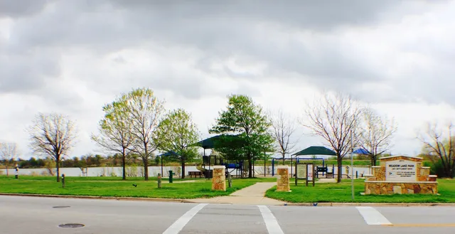 a front view of a building with trees and cars parked