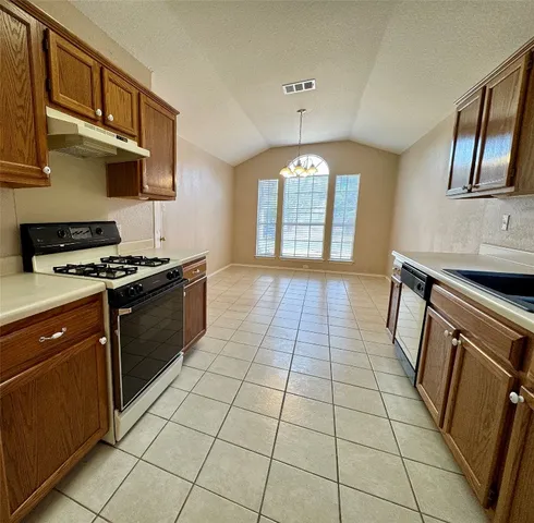 a kitchen with granite countertop a stove a sink and a refrigerator