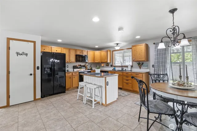 a kitchen with stainless steel appliances granite countertop a refrigerator a sink dishwasher and white cabinets with wooden floor