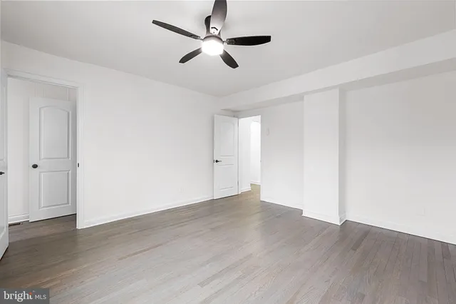 a view of an empty room with wooden floor and window