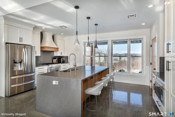 a kitchen with kitchen island a large counter top space a sink stainless steel appliances and cabinets