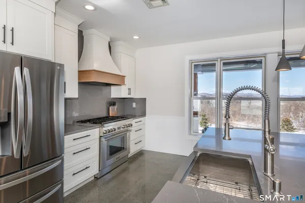 a kitchen with stainless steel appliances granite countertop a stove a refrigerator and a sink with wooden floor