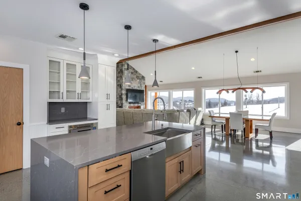 a kitchen with stainless steel appliances granite countertop a sink a stove and a dining table with wooden floor