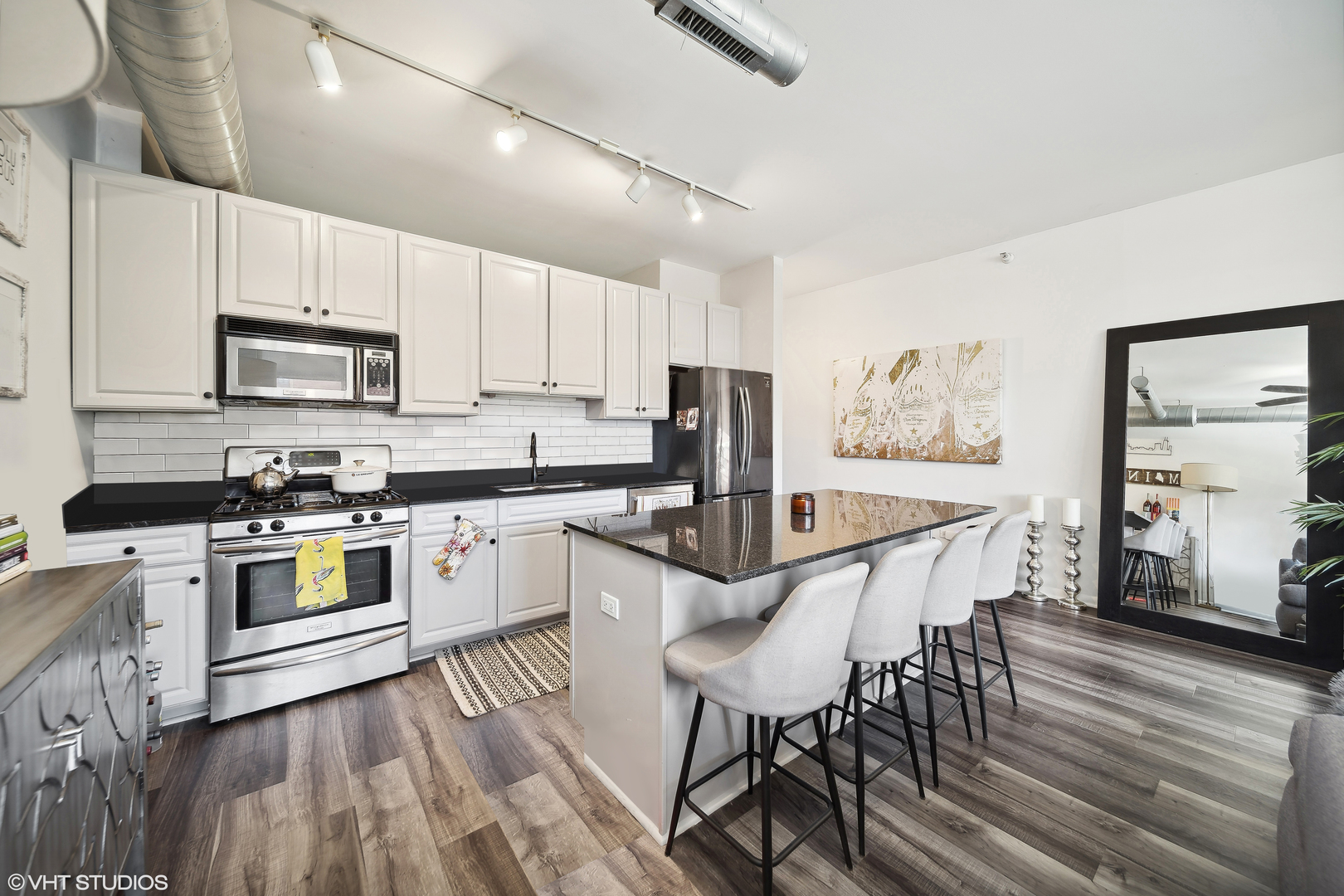 1200 West Monroe Street, Unit 418 Chicago, IL 60607 - Photo 7 of 17 a kitchen with stainless steel appliances granite countertop a stove top oven a sink dishwasher a dining table and chairs with wooden floor