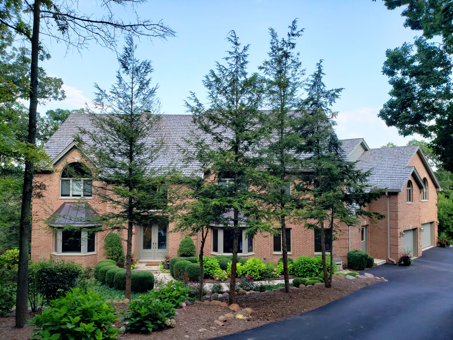 a front view of a house with plants and trees