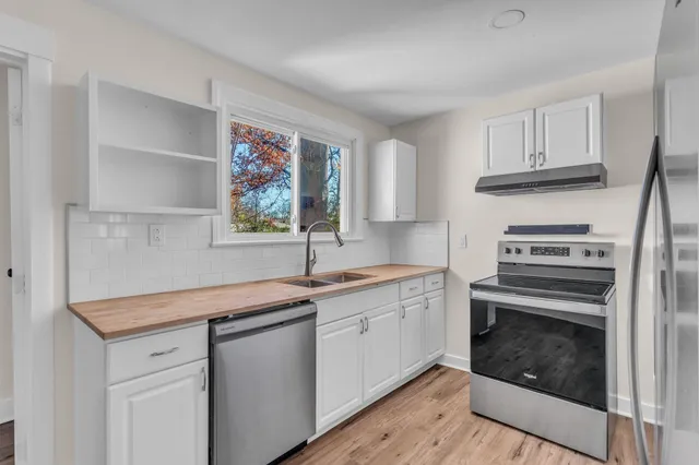 a kitchen with granite countertop a sink cabinets stainless steel appliances and a window