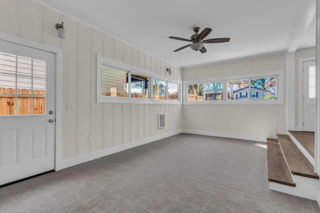 a view of a livingroom with a ceiling fan & windows