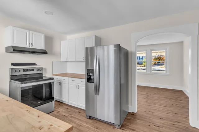 a kitchen with granite countertop a refrigerator stove and wooden floor