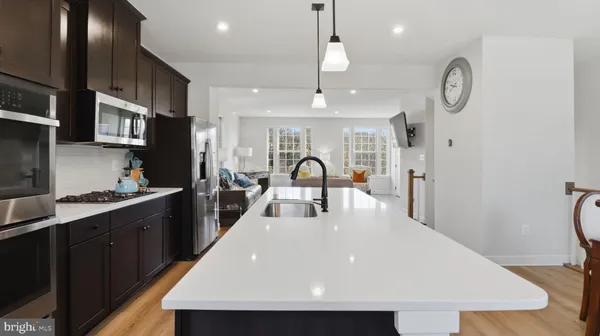 a kitchen with stainless steel appliances a refrigerator a sink dishwasher a oven and a dining table with wooden floor