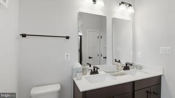 a bathroom with a granite countertop sink toilet a large mirror and a window