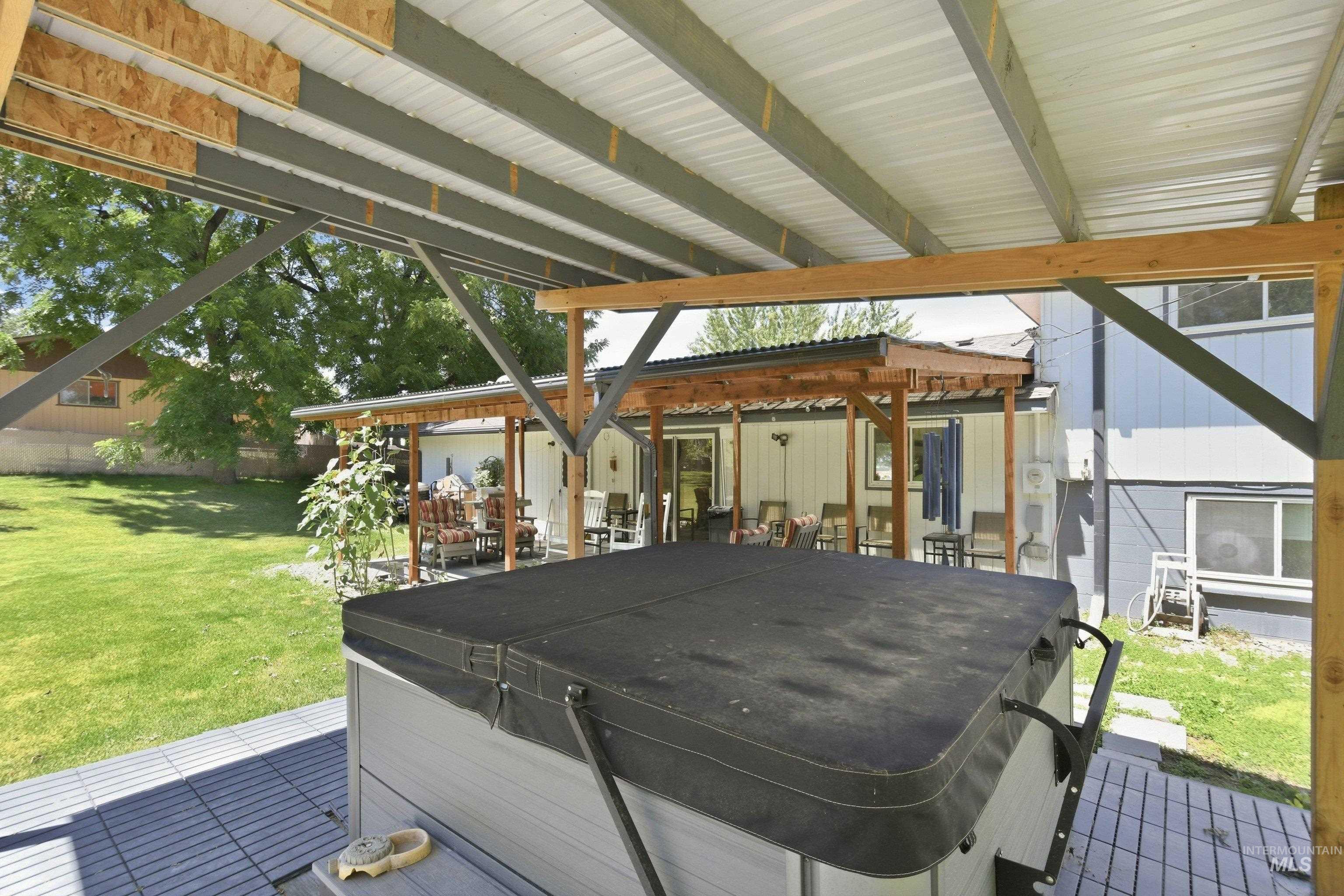 15095 David Street Caldwell, ID 83607 - Photo 29 of 39 Covered outdoor spa area with a gray-tiled surface, supported by a wood and metal beam structure