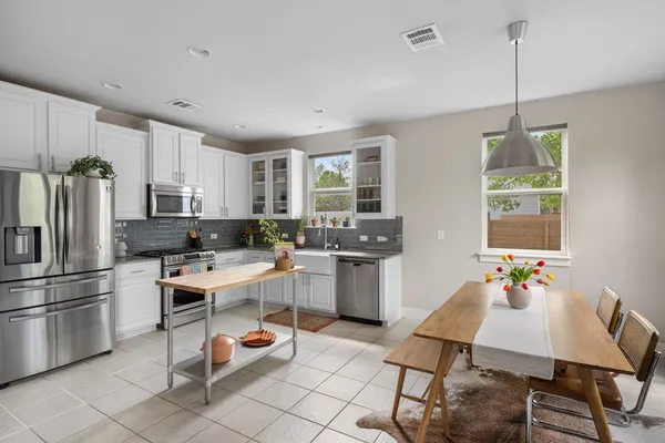 a kitchen with a dining table chairs appliances and cabinets