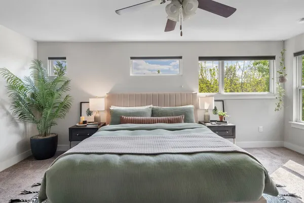 a bedroom with a bed a chandelier and a large window