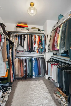 a view of walk in closet with clothes shoes and a large mirror