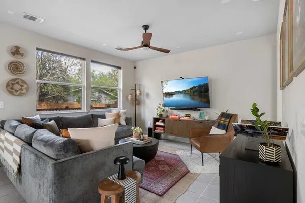 a living room with furniture a flat screen tv and a large window