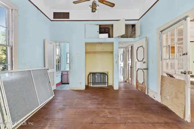 a view of a hallway with wooden floor and a kitchen