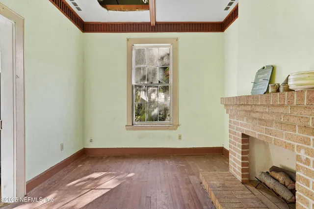 a view of a livingroom with wooden floor and a fireplace