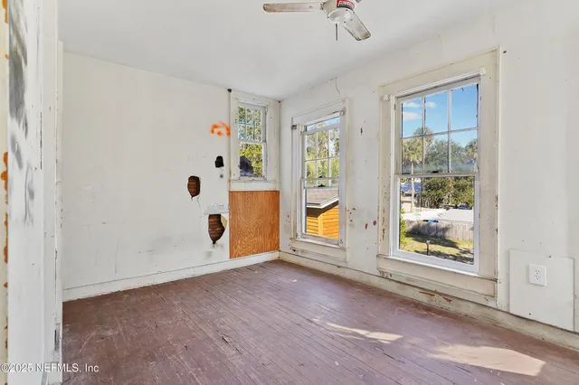 a view of an empty room with a window and wooden floor