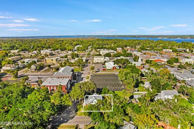 an aerial view of residential houses with outdoor space and trees all around