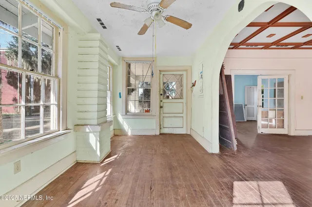 a view of empty room with wooden floor and fan
