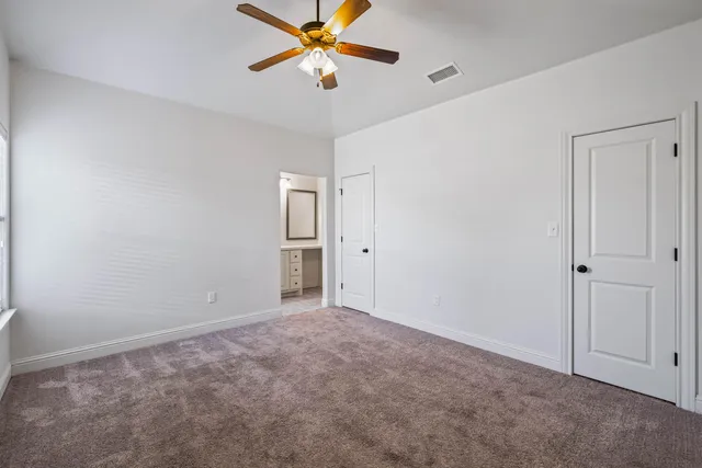 a view of an empty room and chandelier fan
