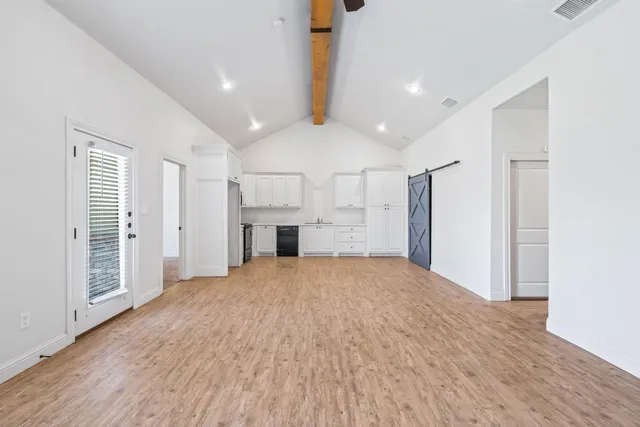 a view of empty room with wooden floor and window