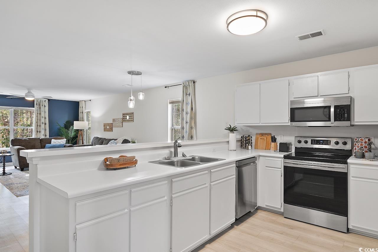 1204 River Oaks Drive, Unit 25D Myrtle Beach, SC 29579 - Photo 31 of 31 Kitchen featuring open floor plan, stainless steel appliances, light countertops, decorative light fixtures, and white cabinetry