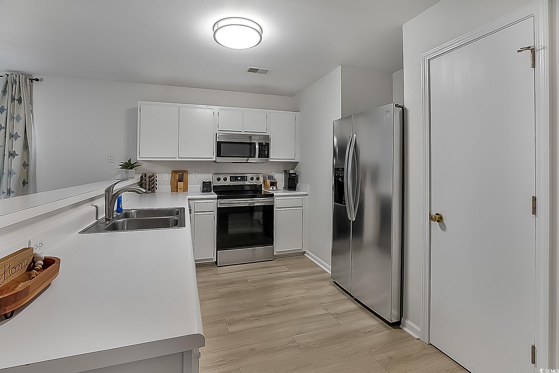 1204 River Oaks Drive, Unit 25D Myrtle Beach, SC 29579 - Photo 9 of 31 Kitchen with light countertops, appliances with stainless steel finishes, white cabinets, and light wood-style flooring