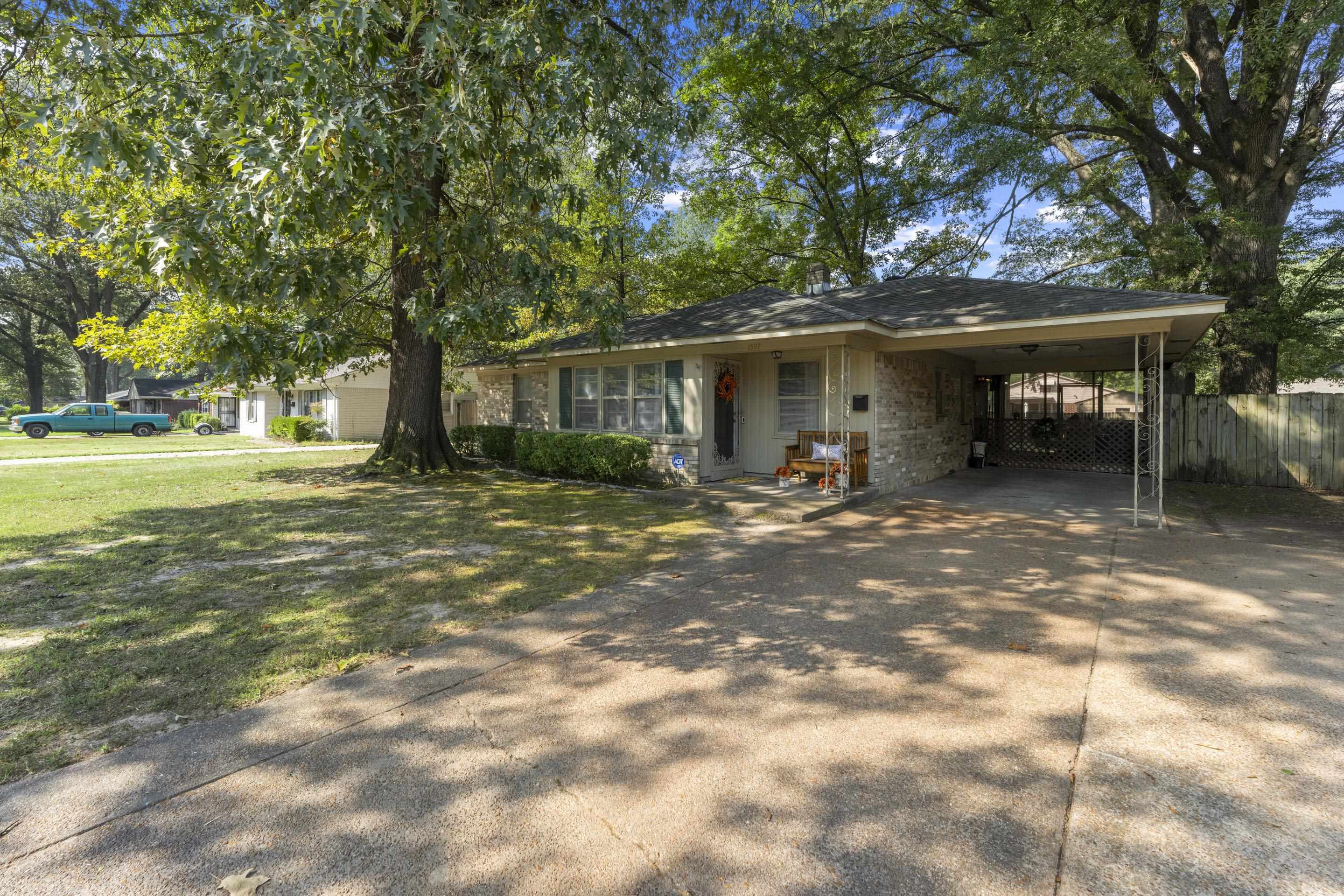 a backyard of a house with table and chairs under an umbrella