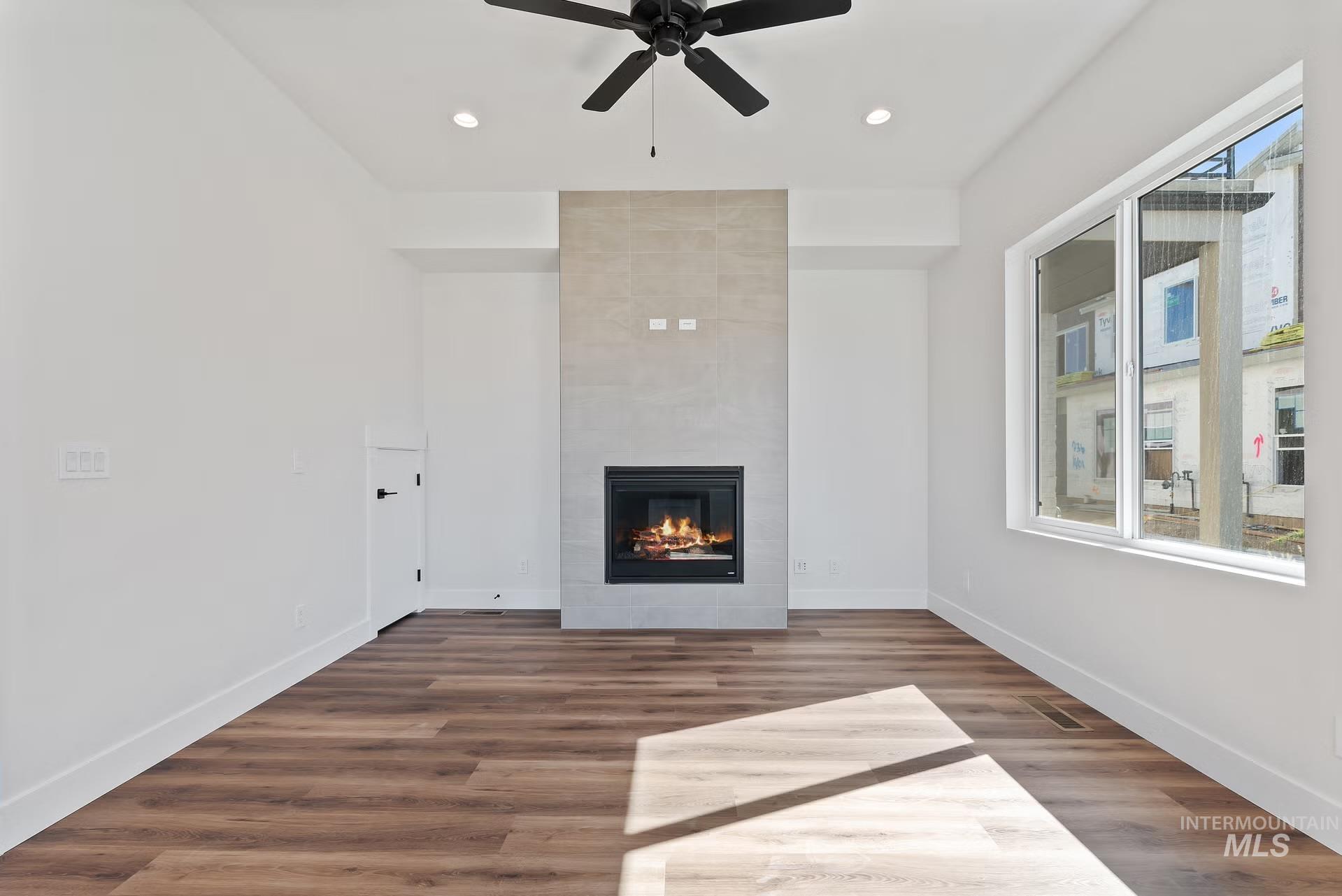 716 South Calhoun Lane Star, ID 83669 - Photo 7 of 23 Unfurnished living room with a fireplace, recessed lighting, dark wood-style flooring, and a ceiling fan