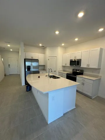 a large kitchen with kitchen island a sink a stove and a refrigerator