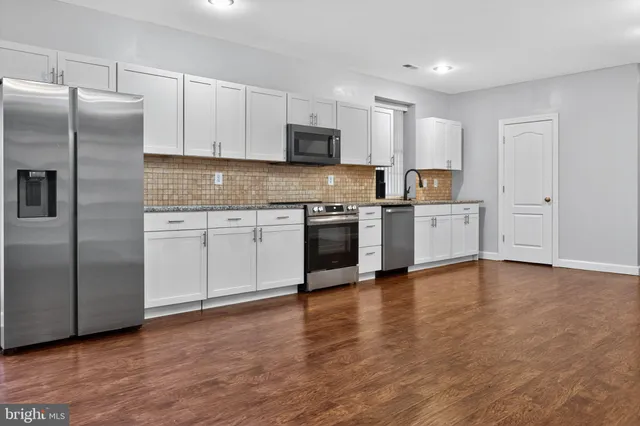 a view of a big room with wooden floor and a kitchen