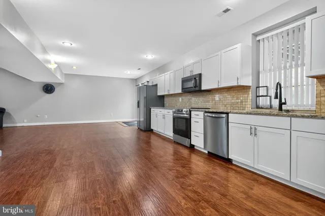 a kitchen with granite countertop white cabinets and stainless steel appliances